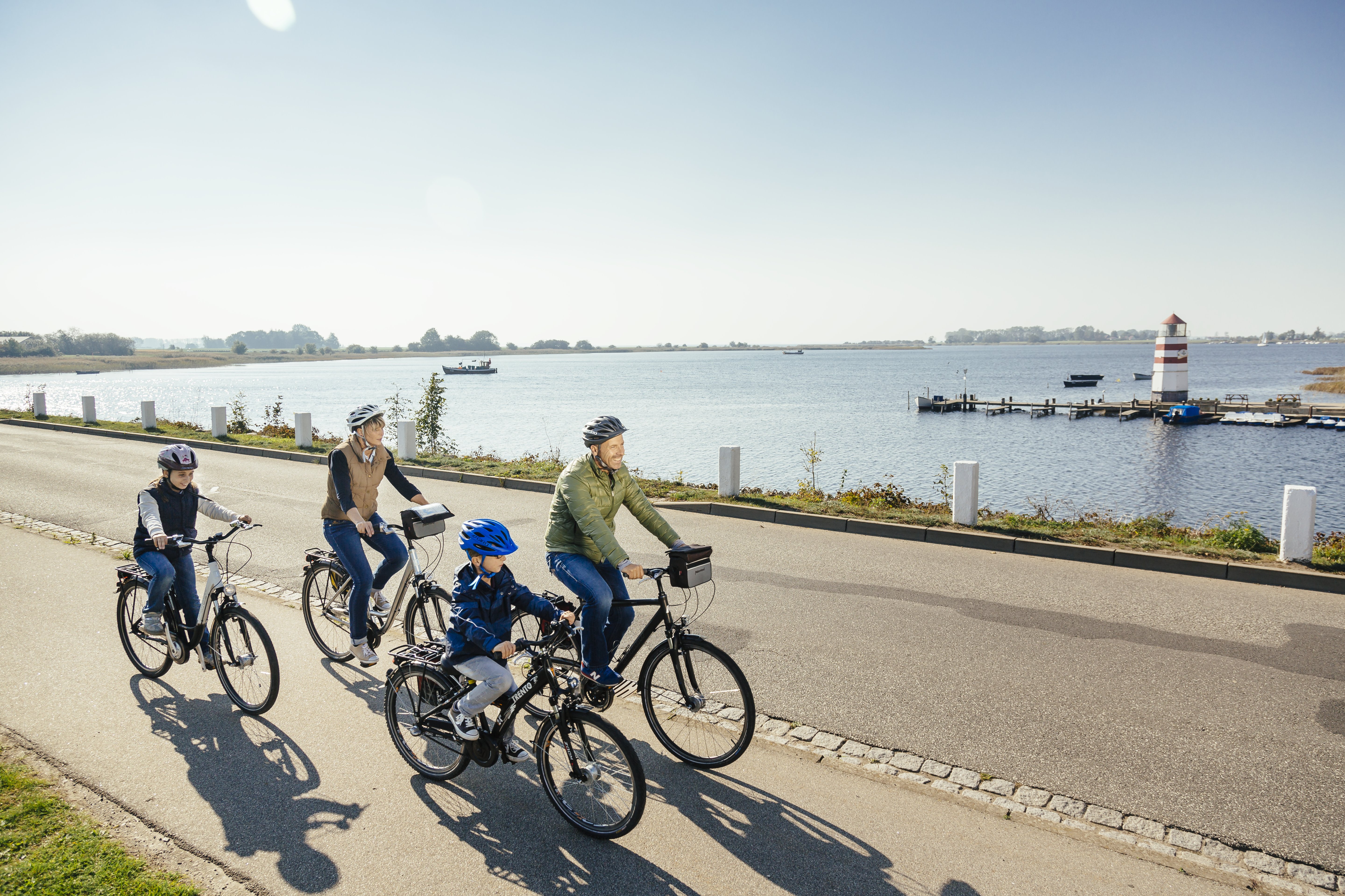 Eine Familie fährt mit dem Fahrrad am Hafen Ummanz entlang